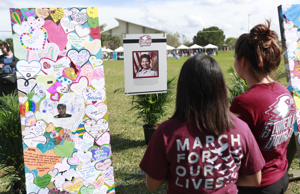 FILE - People at Trails End Park look at a memorial for Martin Duque Anguiano, one of the 17 who were killed during the Marjory Stoneman Douglas High School shooting a year earlier, Thursday, Feb. 14, 2019, in Parkland, Fla. (AP Photo/Wilfredo Lee, File)