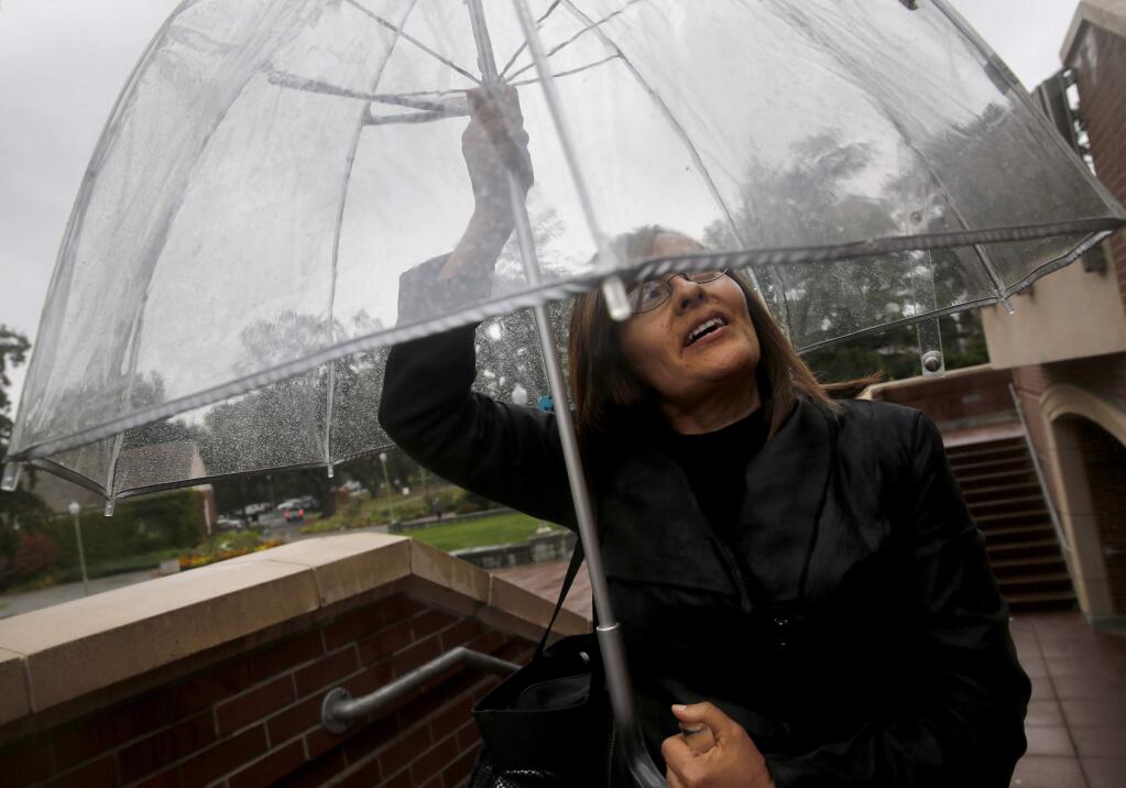 Ilda Lua, an employee in the Santa Rosa Junior College Office of Admissions, tries to stay dry as she walks on campus in Santa Rosa, on Monday, October 3, 2016. (BETH SCHLANKER/ The Press Democrat)