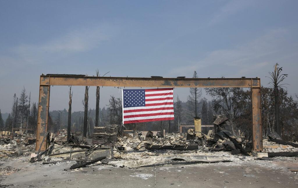 A United States flag hangs from the charred remains of a home in Santa Rosa, Calif. Monday, Oct. 16, 2017. Massive wildfires swept through area last week destroying thousands of homes and businesses and claiming the lives of dozens of people who were unable to escape the flames. (AP Photo/Rich Pedroncelli)