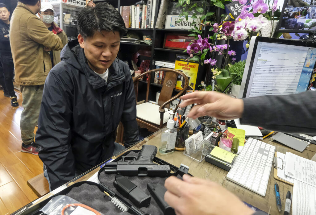 FILE - Brian Xia, 44, picks up his gun at a gun store in Arcadia, Calif., on March 15, 2020. A federal appeals court has ruled that California's ban on the sale of semiautomatic weapons to adults under age 21 is unconstitutional. A panel of the 9th U.S. Circuit Court of Appeals said Wednesday, May 11, 2022, that the law violates the 2nd Amendment right to bear arms. (AP Photo/Ringo H.W. Chiu, File)