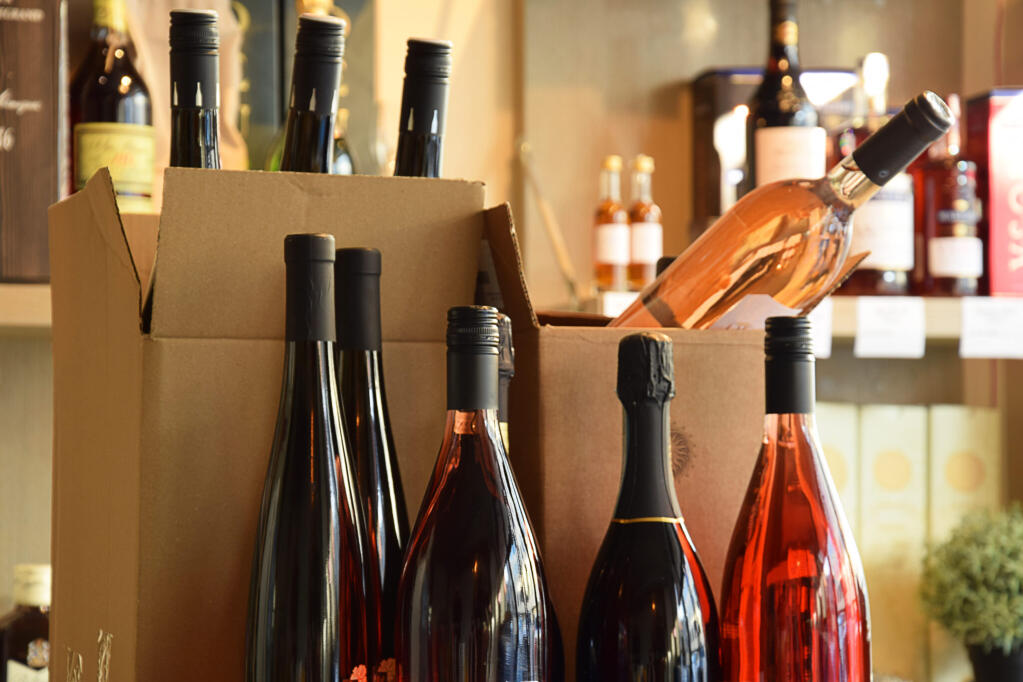 Wine bottles on shelves and in boxes of a wine store, ready for home delivery.