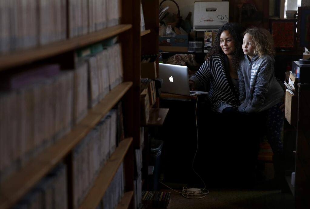 Employee Maleika Dance and her daughter Sevita, 9, play a game on the internet at Occidental Video, which serves as a movie rental and internet cafe, in Occidental, California on Sunday, November 16, 2014. (BETH SCHLANKER/ The Press Democrat)
