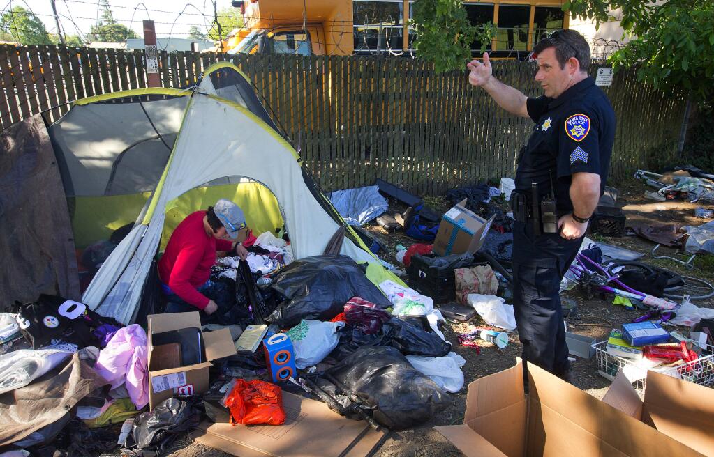 Santa Rosa police Sgt. Jonathan Wolf informs a homeless woman before an emcampment along the Joe Rodota Trail was cleared earlier this year. (JOHN BURGESS / The Press Democrat)