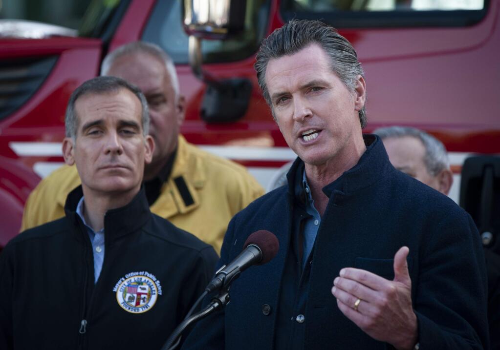 Governor of California Gavin Newsom speaks at a press conference for an update on the Getty Fire, Tuesday, Oct. 29, 2019, in Los Angeles. Los Angeles Mayor Eric Garcetti, left, listens. Authorities are concerned about the possibility that predicted strong winds overnight could pick up embers and start new fires. (AP Photo/Christian Monterrosa)