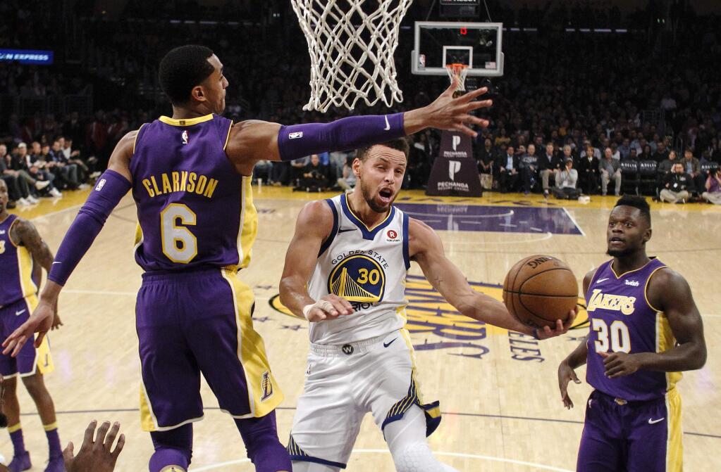 Golden State Warriors guard Stephen Curry, center, goes to the basket while defended by Los Angeles Lakers guard Jordan Clarkson, left, during the first half Wednesday, Nov. 29, 2017, in Los Angeles. (AP Photo/Ringo H.W. Chiu)