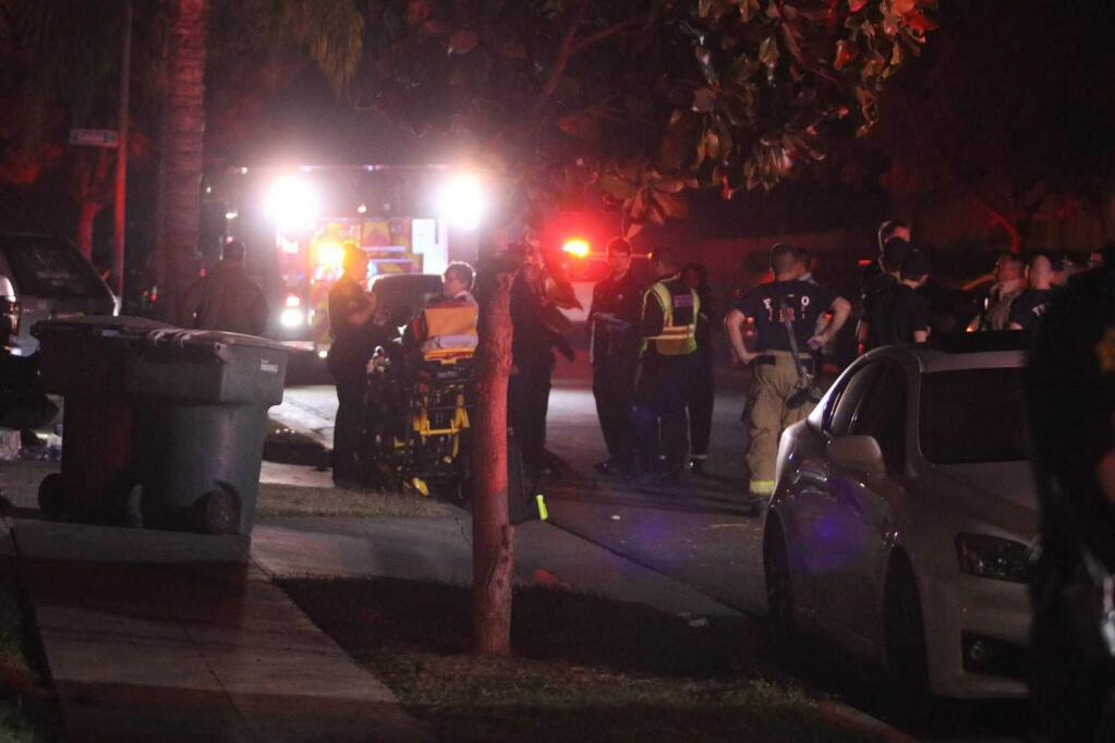 Police and emergency personnel work at the scene of a shooting at a backyard party, Sunday, Nov. 17, 2019, in southeast Fresno, Calif. Multiple people were shot and at least four of them were killed Sunday at a party in Fresno when suspects sneaked into the backyard and fired into the crowd, police said. (Larry Valenzuela/The Fresno Bee via AP)