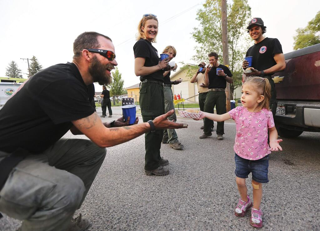 Jonathon Hodgkiss of Lone Peak Engines out of Utah accepts a doughnut and lemonade from Skylee Hatch as fire crews return from fighting a wildfire near the ski town of Brian Head Tuesday, June 27, 2017, in Panguitch, Utah. (Scott G Winterton/The Deseret News via AP)