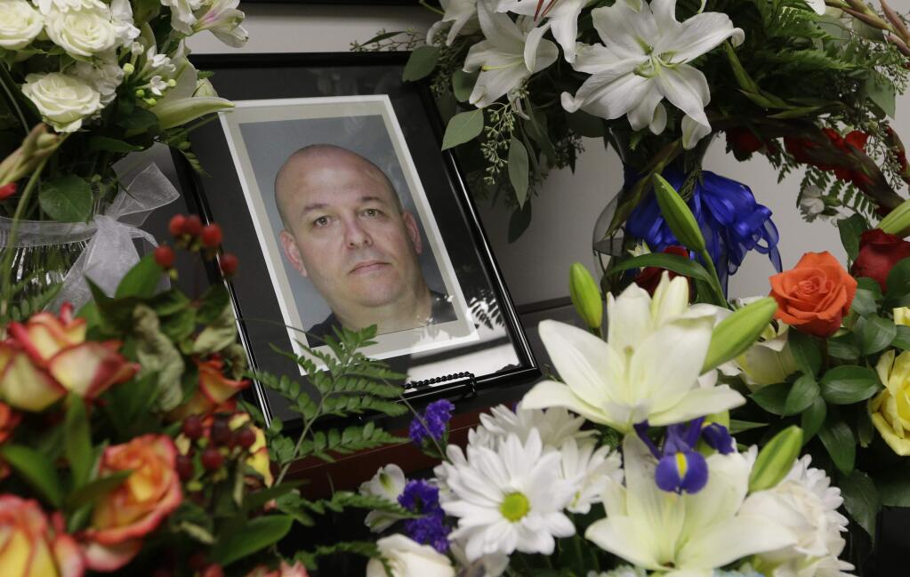 FILE - In this Oct, 28, 2014 file photo, flowers surround a photo of slain Sacramento County Deputy Sheriff Daniel Oliver at the Sacramento County Sheriff's office in Sacramento, Calif. Luis Enrique Monroy Bracamontes, the suspect being tried in the slayings of Oliver and Scott Brown, called Brown a 'coward' as his murder trial began on Tuesday, Jan. 16, 2018. (AP Photo/Rich Pedroncelli, File)