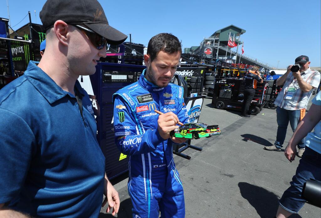 Driver Kyle Larson, right, autographs a model car for fan Cody Gudleske before his practice run for the Toyota/Save Mart 350 at Sonoma Raceway on Friday, June 21, 2019. (Christopher Chung / The Press Democrat)