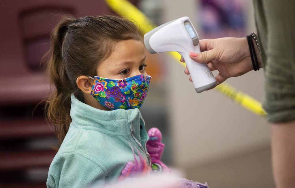 Kacey Menjivar, 4, has her temperature checked before the start of daycare at the North Bay Children's Center at Steele Lane School in Santa Rosa on Thursday, July 23, 2020.   (John Burgess/The Press Democrat)