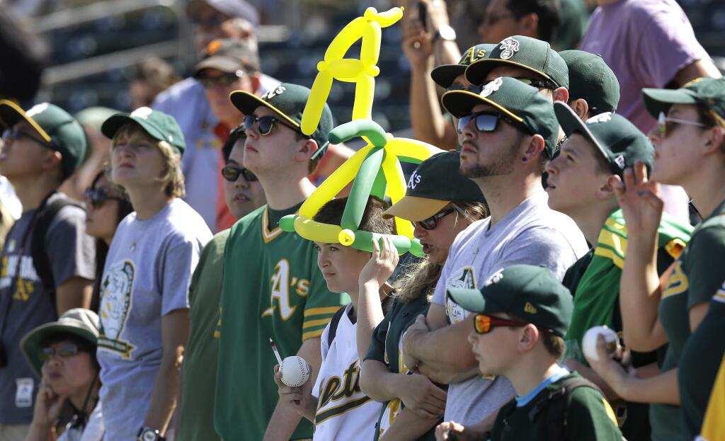 Oakland Athletics fans view batting practice prior to a spring training exhibition baseball game against the San Francisco Giants Saturday, March 14, 2015, in Mesa, Ariz. (AP Photo/Ben Margot)