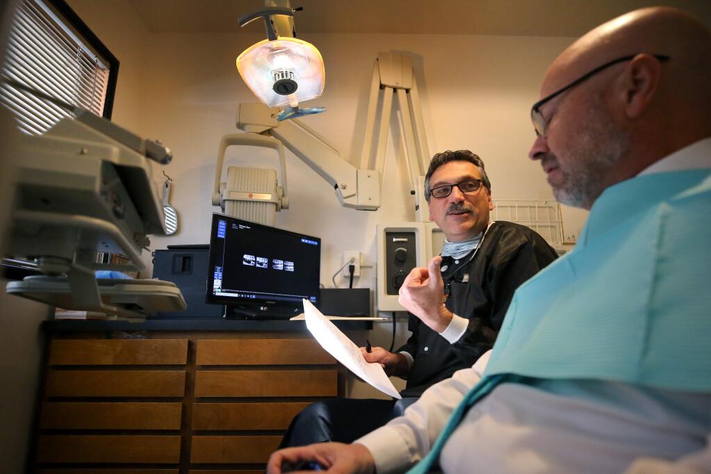 Dr. Anthony Fernandez questions patient Sean Ramsey about his dental hygiene routine before a teeth cleaning at his office in Santa Rosa on Thursday, November 21, 2019. (BETH SCHLANKER/ The Press Democrat)