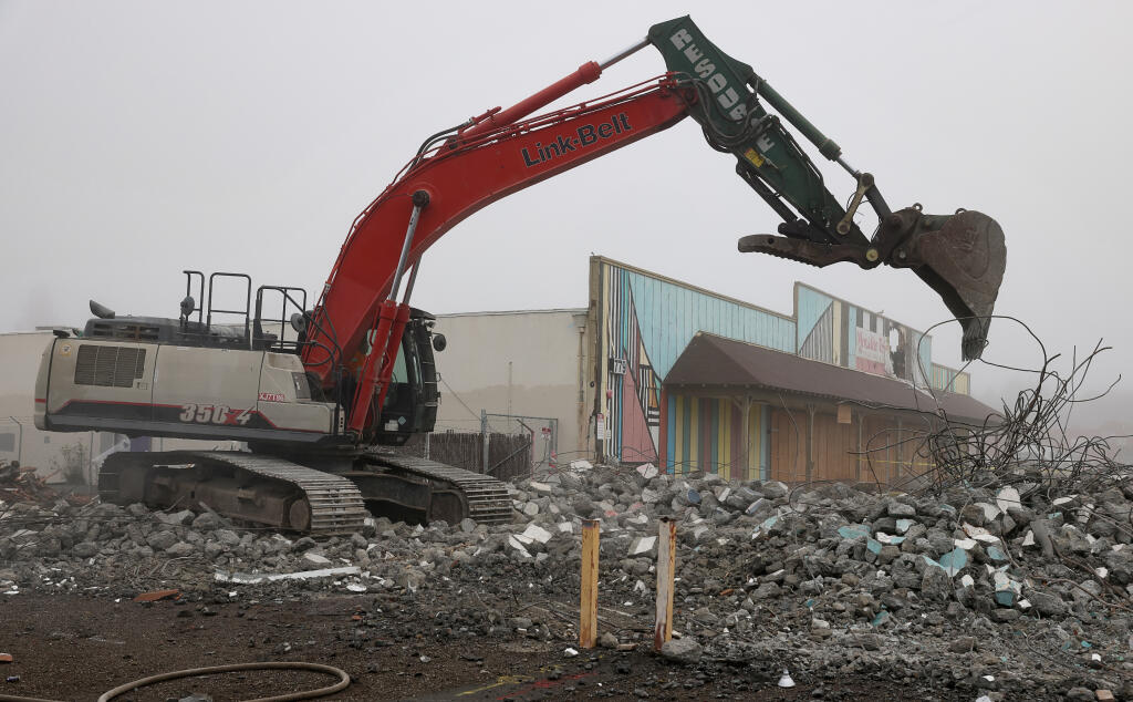 An excavator demolishes a building at the former Roseland Village Shopping Center site in Santa Rosa on Tuesday, Dec. 12, 2023. (Christopher Chung/The Press Democrat)