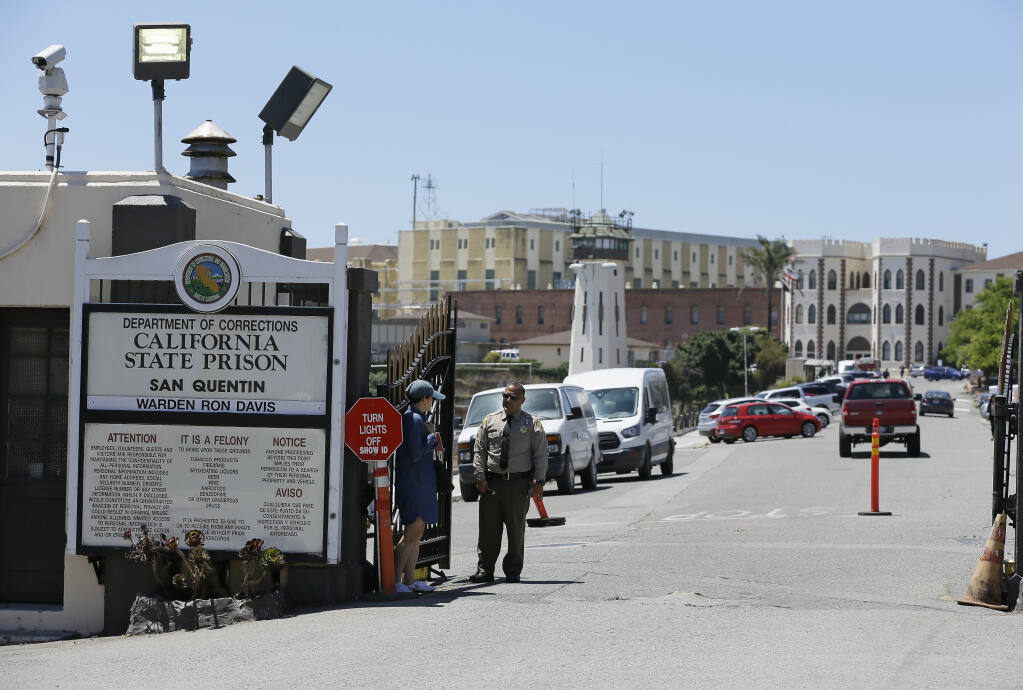 FILE - A Department of Corrections officer guards the main entryway leading into San Quentin State Prison in San Quentin, Calif., July 24, 2019. California lawmakers harshly criticized state corrections officials Wednesday, July 1, 2020, for a "failure of leadership" for botching their handling of the pandemic by inadvertently transferring infected inmates to an untouched prison, triggering the state's worst prison coronavirus outbreak. A third of the 3,500 inmates at San Quentin State Prison near San Francisco have tested positive since officials transferred 121 inmates from the heavily impacted California Institution for Men in Chino on May 30 without properly testing them for infections. (AP Photo/Eric Risberg, File)