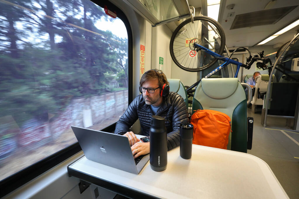 Marcel Molina works on his laptop while commuting on the SMART train in Santa Rosa on Monday, June 12, 2023.  (Christopher Chung/The Press Democrat)