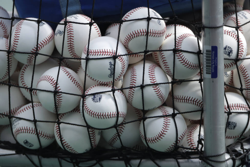 FILE — In this July 3, 2020, file photo, balls marked with Cactus League spring training logos are in a basket during Kansas City Royals baseball practice at Kauffman Stadium in Kansas City, Mo. Major League Baseball has slightly deadened its baseballs amid a years-long surge in home runs. MLB anticipates the changes will be subtle, and a memo to teams last week cites an independent lab that found the new balls will fly 1 to 2 feet shorter on balls hit over 375 feet. (AP Photo/Charlie Riedel, File)