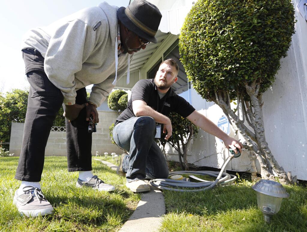 FILE -- In this March 11, 2014 file photo Steve Upton, right, demonstrates how to use the water timer he installed on the water spigot at the home of Larry Barber, left, in Sacramento, Calif. Upton, an inspector for the water conservation unit of the Sacramento Utilities Department, follows up on tips concerning city residents wasting water in one of California's driest years on record. (AP Photo/Rich Pedroncelli,file)
