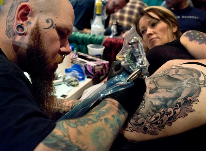 Tattoo artist Mike Hughes of Electric Monk Tattoo works on a tattoo on the thigh of Colleen Acree of Santa Rosa during Izzy's 23rd annual Santa Rosa Tattoos and Blues in Santa Rosa, Calif., on March 1, 2014. (Alvin Jornada / The Press Democrat)
