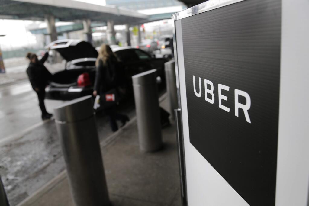 File- In this March 15, 2017, file photo, a sign marks a pick-up point for the Uber car service at LaGuardia Airport in New York. (AP Photo/Seth Wenig, File)