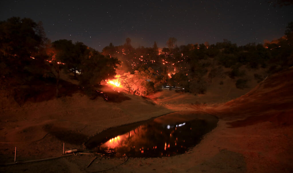 A drought starved farm pond, nearly 30 feet below normal, is ringed by the Pope fire in Napa County, Friday, Oct. 23, 2020. (Kent Porter / The Press Democrat) 2020