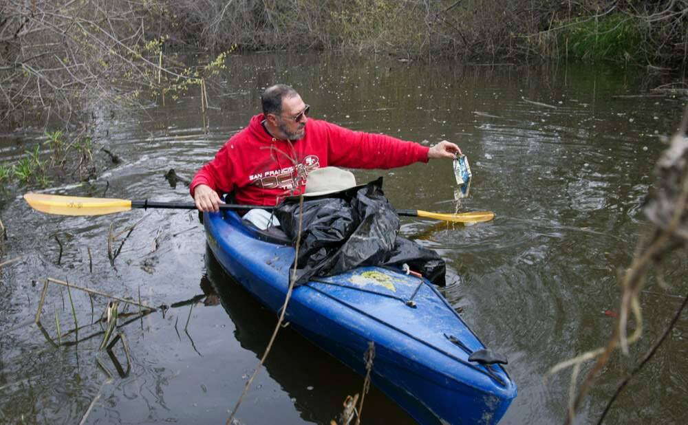 Bruce Cohn works to clean up the upper stretch of the Petaluma River by picking up trash as he kayaks on the high tide on Thursday morning March 7, 2013. Scott Manchester / The Press Democrat