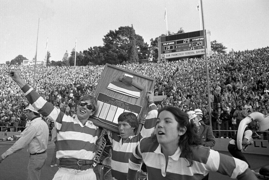 In this Nov. 20, 1982, file photo, the Stanford band goes wild on the field at the end of the Cal-Stanford game in Berkeley, thinking they had won, as the scoreboard says 20-19 with no time left. Known simply as The Play, Cal used five laterals and had to run over a Stanford trombone player to score the winning touchdown on the last play of the game in 1982. Stanford still does not acknowledge the victory and insists the play was illegal. (AP Photo/Carl Viti, File)