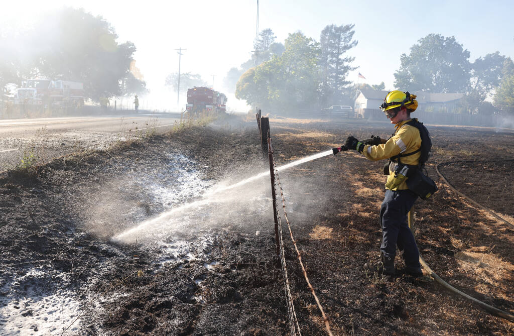Matt Rinehart, with Sonoma County Fire fights a grass fire along Llano Road, north of Todd Road, in Santa Rosa on Tuesday, Aug. 10, 2021.  (Christopher Chung/ The Press Democrat)