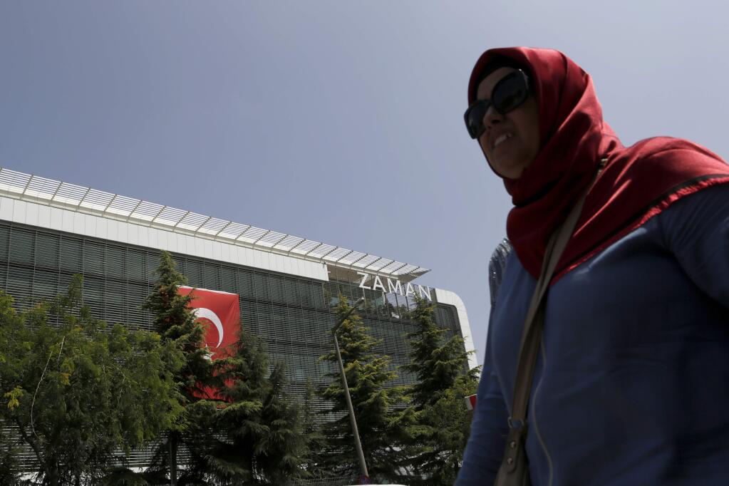 A woman walks past the headquarters of 'Zaman' newspaper, after being closed by the government in Istanbul, Thursday, July 28, 2016. The European Union has called the crackdown on media in Turkey 'worrying' and warned Ankara to respect fundamental freedoms. (AP Photo/Petros Karadjias)