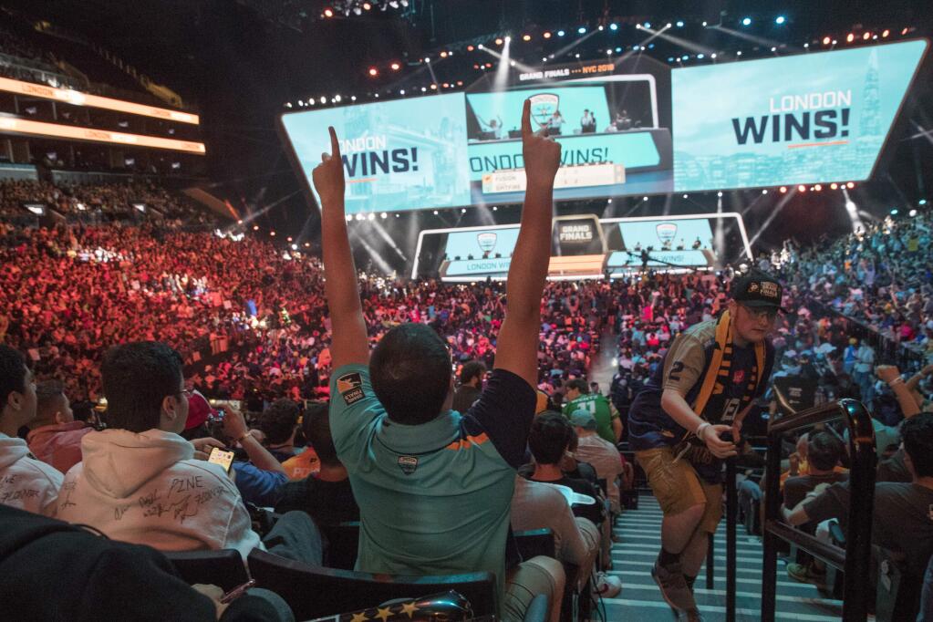 FILE - In this July 28, 2018, file photo, London Spitfire fan Rick Ybarra, of Plainfield, Ind., reacts after London won the second game against the Philadelphia Fusion during the Overwatch League Grand Finals competition at Barclays Center in New York. A new venture backed by many of video gaming's biggest publishers is unveiling a network that hopes to be to esports what ESPN has been to traditional sports. VENN is set to launch in 2020 and aims to give the fragmented esports scene a home base for content with higher production value than gamers are used to with online streaming. (AP Photo/Mary Altaffer, File)
