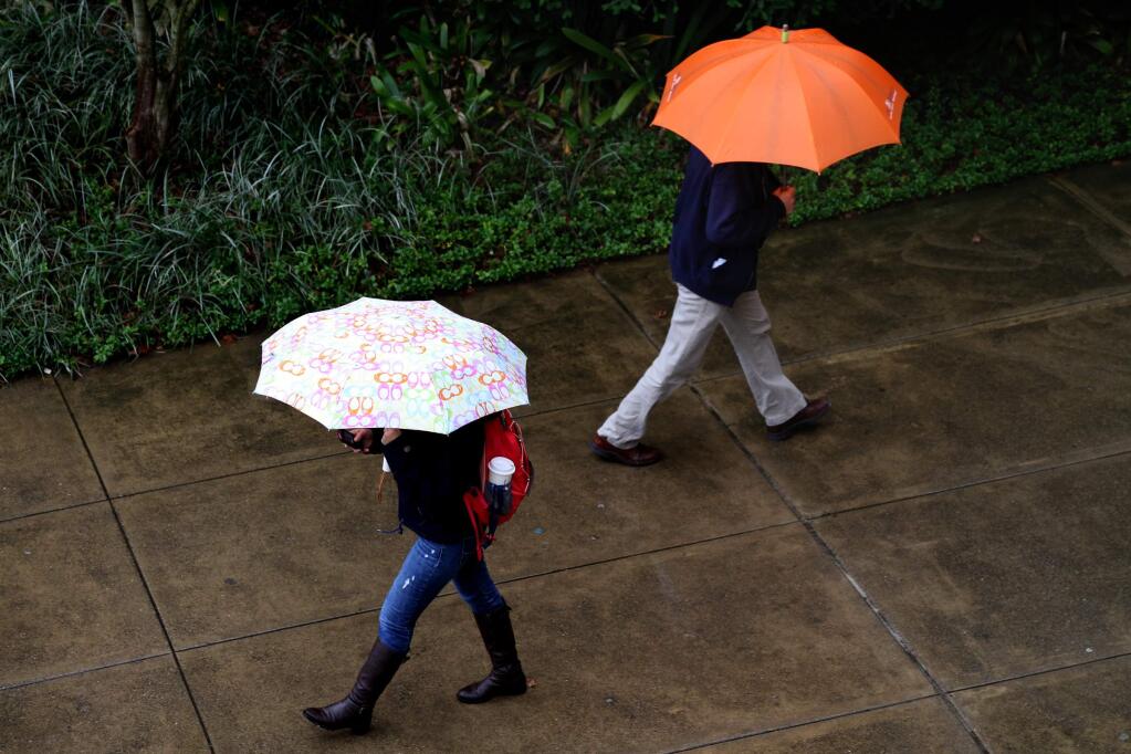 People try to stay dry as they walk on the Sonoma State University campus in Rohnert Park. (BETH SCHLANKER/ The Press Democrat, file)