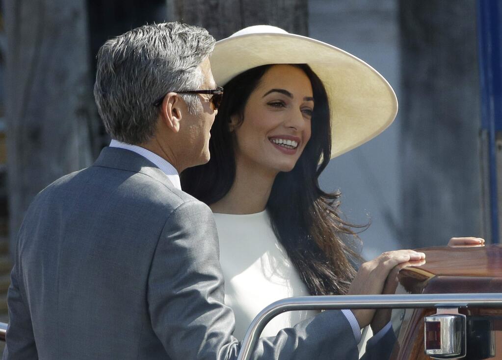 George Clooney and Amal Alamuddin leave Venice's city hall, Italy, Monday, Sept. 29, 2014. Clooney and Amal married Saturday, Sept. 27, the actor's representative said, out of sight of pursuing paparazzi and adoring crowds.(AP Photo/Andrew Medichini)