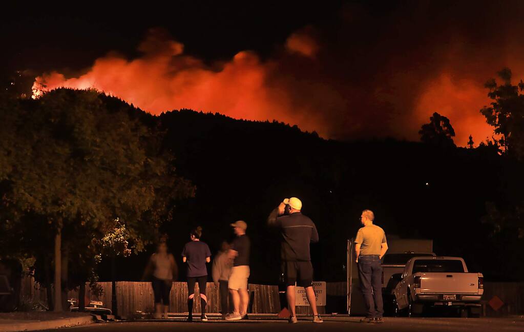 Waken in the dead of night on an order to evacuate, Skyhawk residents watch the glow of an approaching fire from their Skyhawk Homes near Los Alamos Road in Santa Rosa, Saturday Oct. 14, 2017. They eventually left the area. (Kent Porter / The Press Democrat) 2017