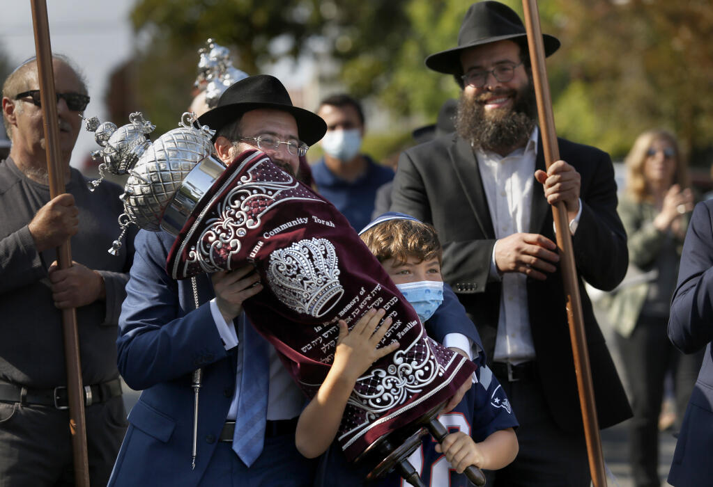 Rabbi Dovid Bush and Simon Goldstein, 8,  carry a newly finished Torah scroll in a procession from Penry Park to the Chabad Jewish Center in Petaluma on Sunday, Aug. 22, 2021. (BETH SCHLANKER/THE PRESS DEMOCRAT)
