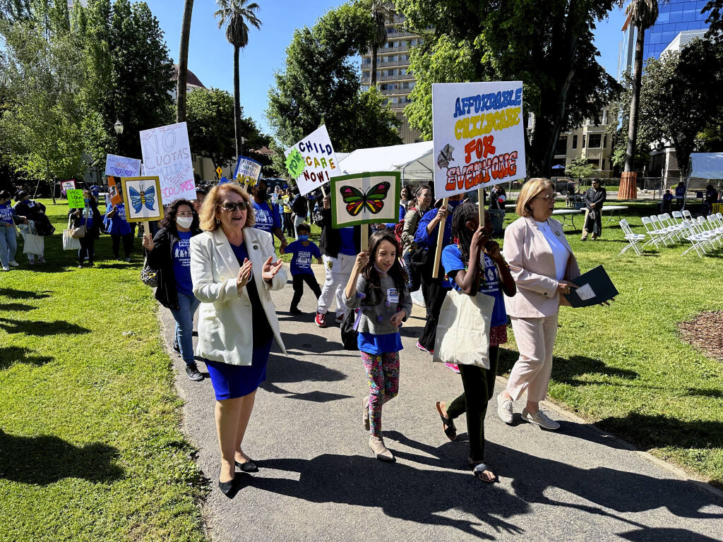 California Assembly Majority Leader Eloise Gomez Reyes, left, and Democratic Assemblymember Cecilia Aguiar-Curry, right, march with parents and others who support the state's subsidized child care programs on Wednesday, May 10, 2023, in Sacramento, California. Gov. Gavin Newsom will announce his updated budget plan on Friday, May 12, 2023. Newsom has proposed delaying funding for about 20,000 subsidized child care slots. (AP Photo/Adam Beam).