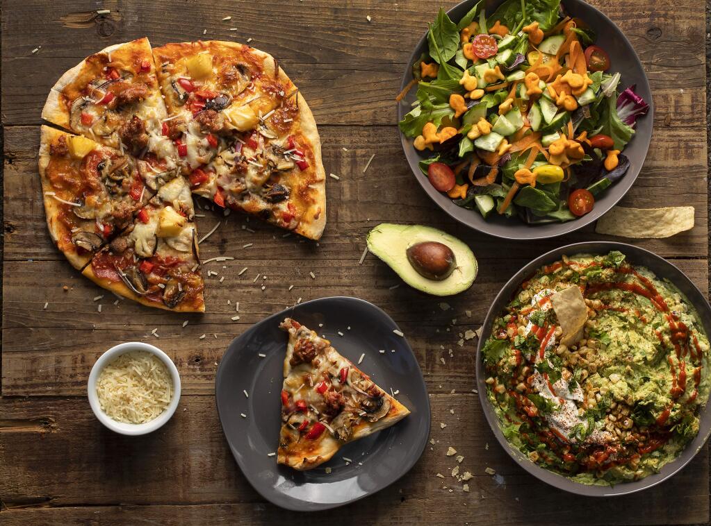 Clockwise from top left, homemade grilled pizza, a garden salad with goldfish and Mexican street corn-inspired guacamole by mother/son cooking team Amy and Cannon Meiers. (John Burgess/The Press Democrat)