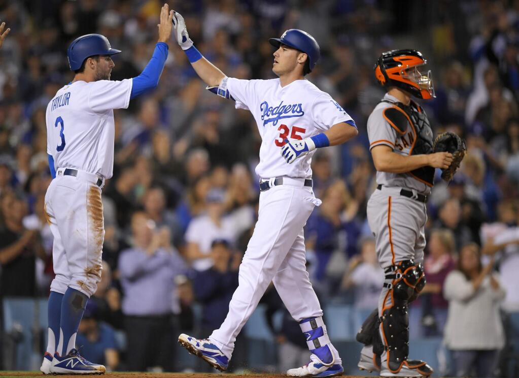 Los Angeles Dodgers' Cody Bellinger, center, is congratulated by Chris Taylor, left, after hitting a three-run home run as San Francisco Giants catcher Nick Hundley stands at the plate during the third inning of a baseball game, Friday, Sept. 22, 2017, in Los Angeles. (AP Photo/Mark J. Terrill)