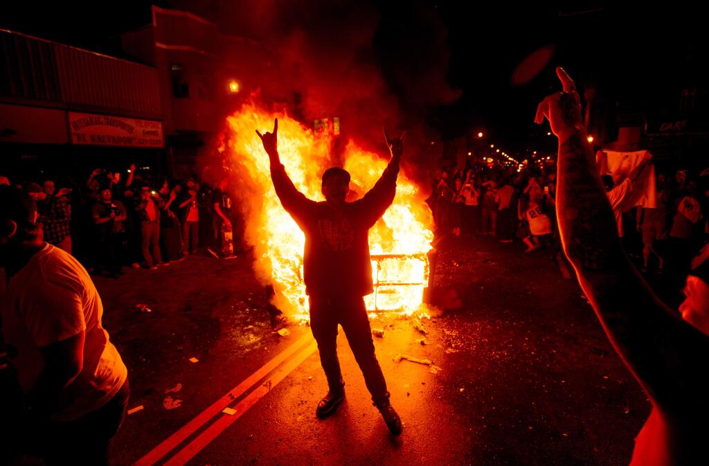 A man celebrates in front of a burning couch in the Mission district after the San Francisco Giants beat the Kansas City Royals to win the World Series on Wednesday, Oct. 29, 2014, in San Francisco. (AP Photo/Noah Berger)