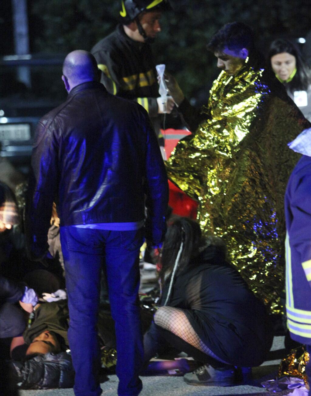 People stand in front of a bodie lying on the ground outside disco Lanterna Azzurra in Corinaldo, central Italy, Saturday, Dec. 8, 2018. A stampede at a rap concert in an overcrowded disco in central Italy killed five young teenagers and a woman who had accompanied her daughter to the event early Saturday, police said, adding that 59 people were injured. (AP Photo/Bobo Antic)