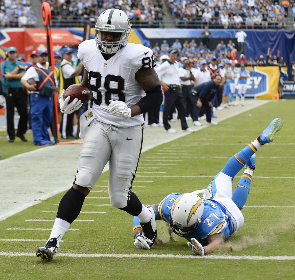 FILE - In this Oct. 25, 2015, file photo, Oakland Raiders wide receiver Amari Cooper, left, scores a touchdown as San Diego Chargers strong safety Jimmy Wilson (27) cannot reach him during the first half of an NFL football game, in San Diego. The Associated Press will announce its 2015 NFL award winners the night before the Super Bowl. With the schedule halfway done, it looks like a two-man race between Oakland receiver Amari Cooper and St. Louis running back Todd Gurley for offensive rookie. (AP Photo/Denis Poroy, File)