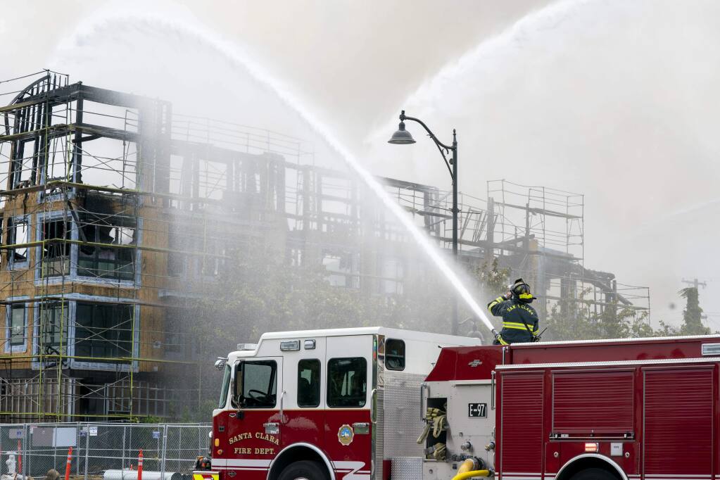 Santa Clara firefighters pour water on a building under construction in Santa Clara, Calif., on Friday, June 28, 2019, The four-alarm fire, which generated towering plumes of black smoke, began Friday morning. (AP Photo/Tony Avelar)