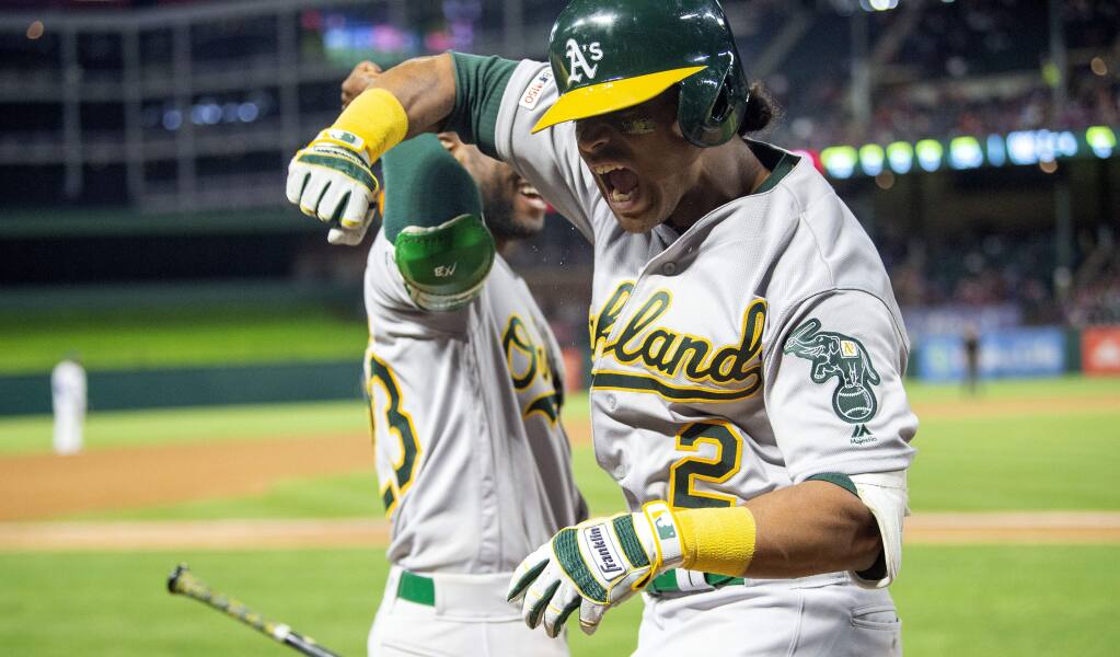 The Oakland Athletics' Khris Davis, right, celebrates with Jurickson Profar after hitting a solo home run off Texas Rangers relief pitcher Chris Martin during the eighth inning Friday, April 12, 2019, in Arlington, Texas. (AP Photo/Jeffrey McWhorter)