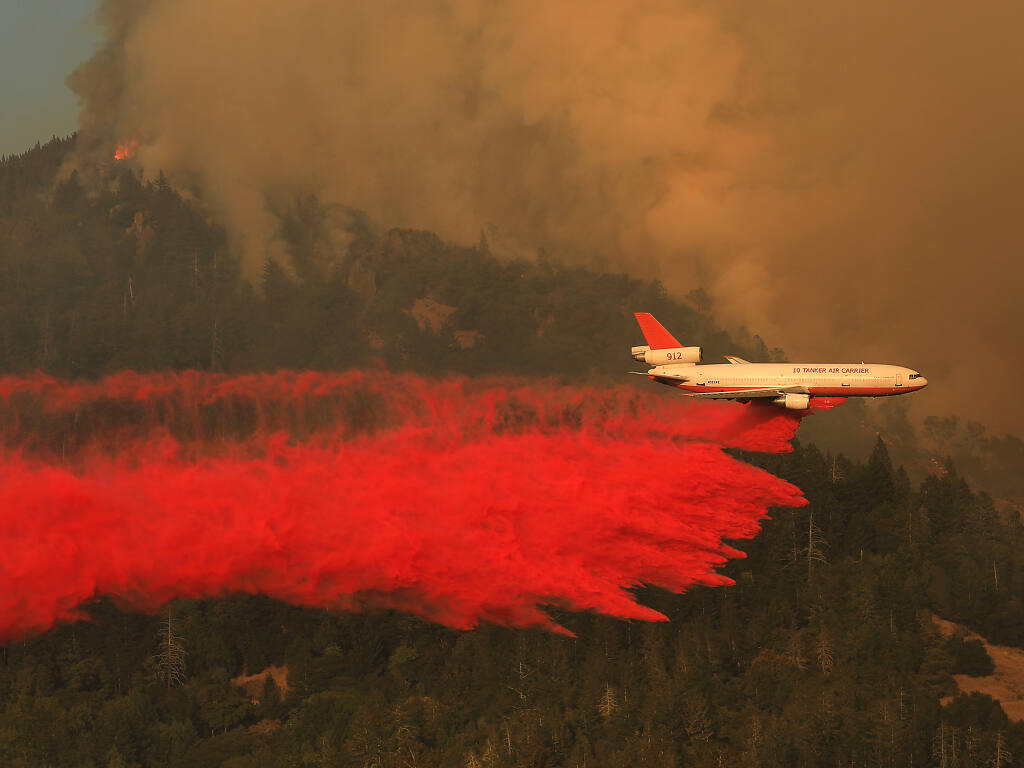 Natural disasters such as 2020’s Glass Fire, which damaged or destroyed over two dozen wineries in Napa and Sonoma counties are a key driver in the expected rise of commercial property policy rates by an average of 13.6% this year. In this photo, a QA DC-10 drops retardant on the west slope of Mt. St. Helena during the Glass Fire on Sept. 30, 2020. (Kent Porter / The Press Democrat)
