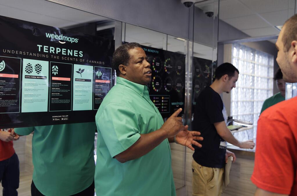 In this Sept. 8, 2017, photo, Frank Hawkins speaks with patrons at the Nevada Wellness Center marijuana dispensary in Las Vegas. The former running back for the Raiders has two things that set him apart from most football players, a Super Bowl ring and a thriving pot shop just off the glittering Las Vegas Strip. (AP Photo/John Locher)