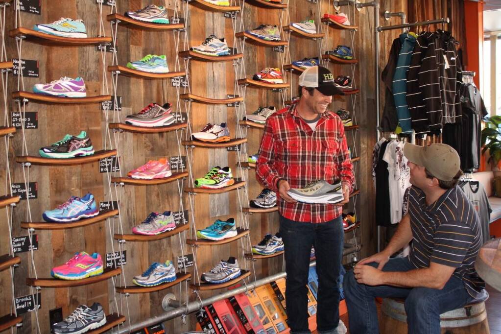 PHOTO: 1 by ANN CARRANZA-Owner Skip Brand shows a shoe to a client at Healdsburg Running Company.