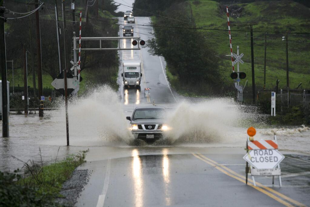 A truck drives through the water running over Ely Road North just south of Old Redwood Highway during heavy rains on Thursday, December 11, 2014. (SCOTT MANCHESTER/ARGUS-COURIER STAFF)