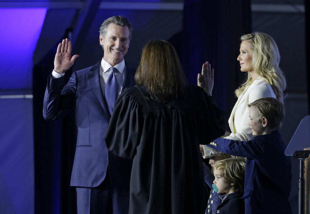 FILE - In this Jan. 7, 2019, file photo California Gov. Gavin Newsom takes the Oath of Office from state Supreme Court Chief Justice Tani Gorre Cantil-Sakauye during his inauguration in Sacramento, Calif. California's new governor won't be living in the historic governor's mansion after all. The Sacramento Bee reported Friday, Jan. 18, 2019, that the family plans to move to a $3.7 million, six-bedroom house in a Sacramento suburb. The newspaper cited property records showing the family bought the Fair Oaks home in December. (AP Photo/Rich Pedroncelli, File)