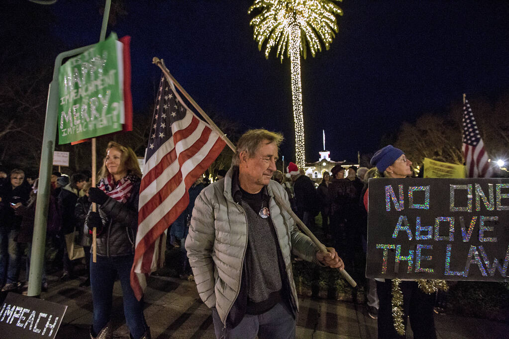 Mike Smith shoulders an American Flag at a pro-impeachment rally on the Plaza on Tuesday, Dec. 17, 2019, joining other rallies held across the country. (Photo by Robbi Pengelly/Index-Tribune)