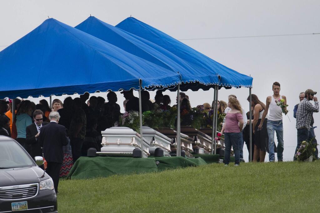 FILE – In this May 3, 2016, file photo, mourners gather around caskets for six of the eight members of the Rhoden family found shot April 22, 2016, at four properties near Piketon, Ohio, during funeral services at Scioto Burial Park in McDermott, Ohio. Authorities say Tuesday, Nov. 13, 2018, that a family of four has been arrested in in the slayings of eight members of one family in rural Ohio two years ago. (AP Photo/John Minchillo, File)