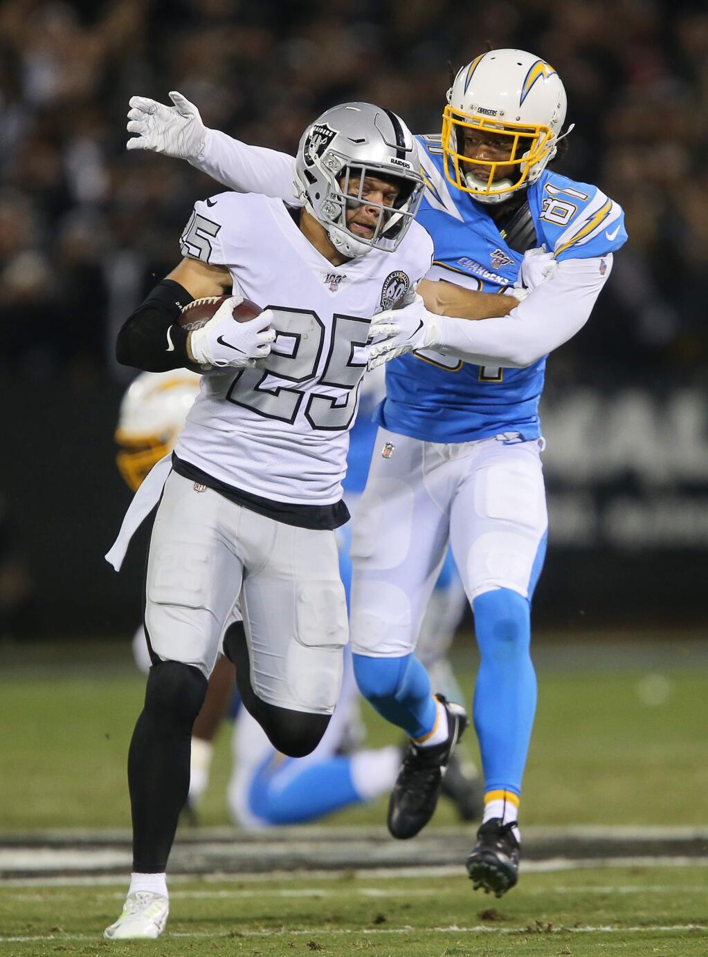 Oakland Raiders free safety Erik Harris tries to evade Los Angeles Chargers wide receiver Mike Williams after intercepting a pass during their game in Oakland on Thursday, November 7, 2019. (Christopher Chung/ The Press Democrat)