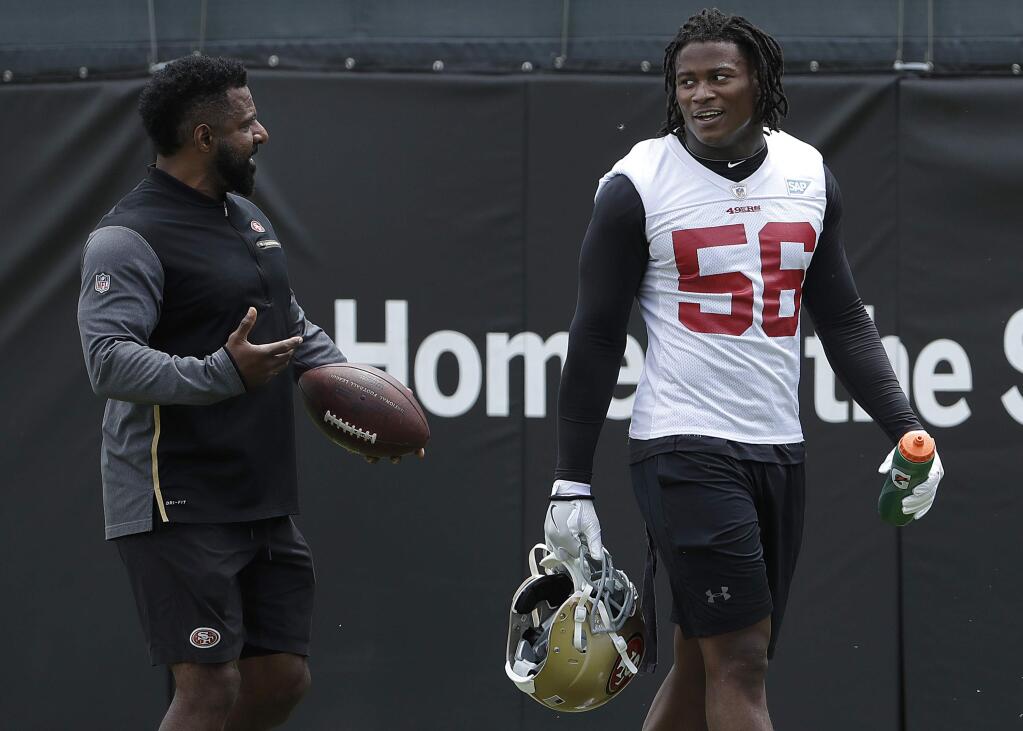 In this May 30, 2018, file photo, San Francisco 49ers linebacker Reuben Foster (56) walks on the field with assistant coach Ray Wright during a practice at the team's training facility in Santa Clara. (AP Photo/Jeff Chiu, File)